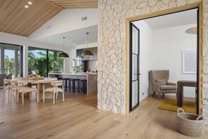 A modern interior with a dining area, kitchen, and seating space. - Hapuna Estates 10 Four Bedroom (Kamuela)
