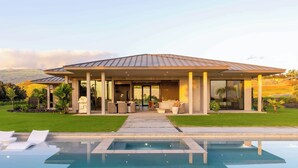 Een modern huis met een zwembad, terras en uitzicht op de heuvels.