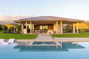 A modern house with a swimming pool, outdoor seating, and a view of the hills. - Hapuna Estates 10 Four Bedroom (Kamuela)