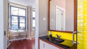 Ein modernes Badezimmer mit einem schwarzen Waschbecken, gelben Fliesen und einem großen Spiegel.