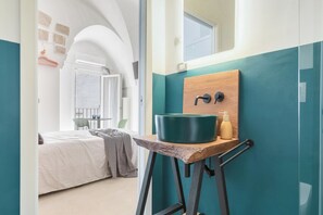 Ein modernes Badezimmer mit einer türkisfarbenen Akzentwand, einem Holzkosmetikschrank mit Waschbecken und einem Spiegel darüber.