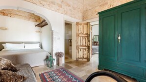 Quarto com cama, guarda-roupa verde e tapete estampado.