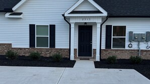 A two-story house with a dark roof, white siding, and a black front door. - 2-bedroom townhome in South Augusta (Augusta)
