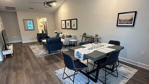 A modern living room with a dining area, wooden flooring, a ceiling fan, and a framed picture on the wall. - 2-bedroom townhome in South Augusta (Augusta)