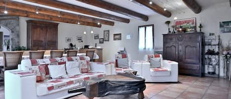 A spacious living area with a white sofa set, a wooden coffee table, and a stone fireplace.
