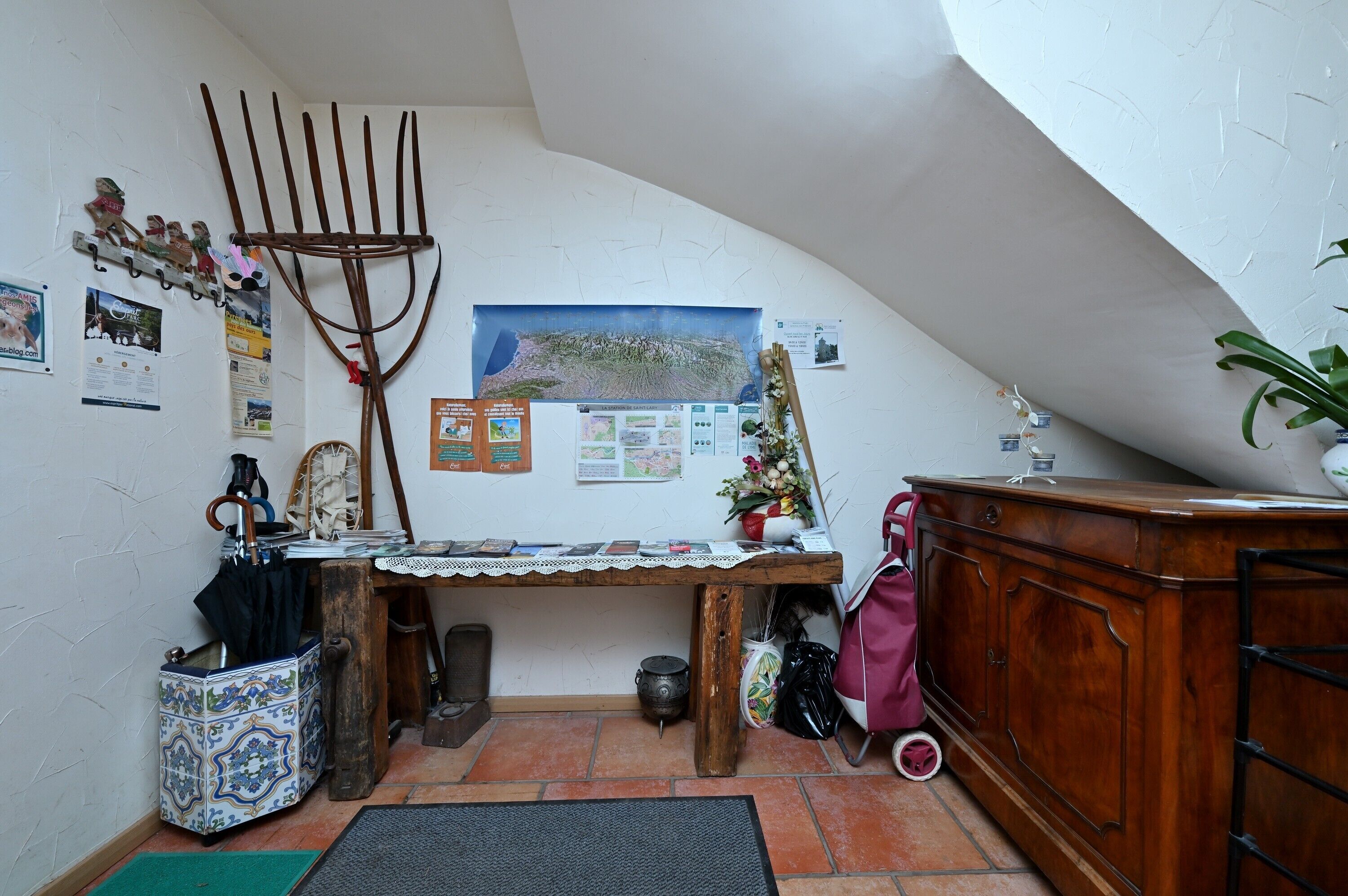 A room with a sloped ceiling, a wooden desk with a map, a coat rack, and a cabinet.