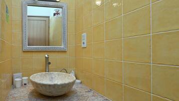 Un bagno con piastrelle gialle, un lavabo capiente, uno specchio e un rubinetto.