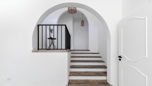 Una escalera de madera con barandal negro que conduce a un arco de entrada.