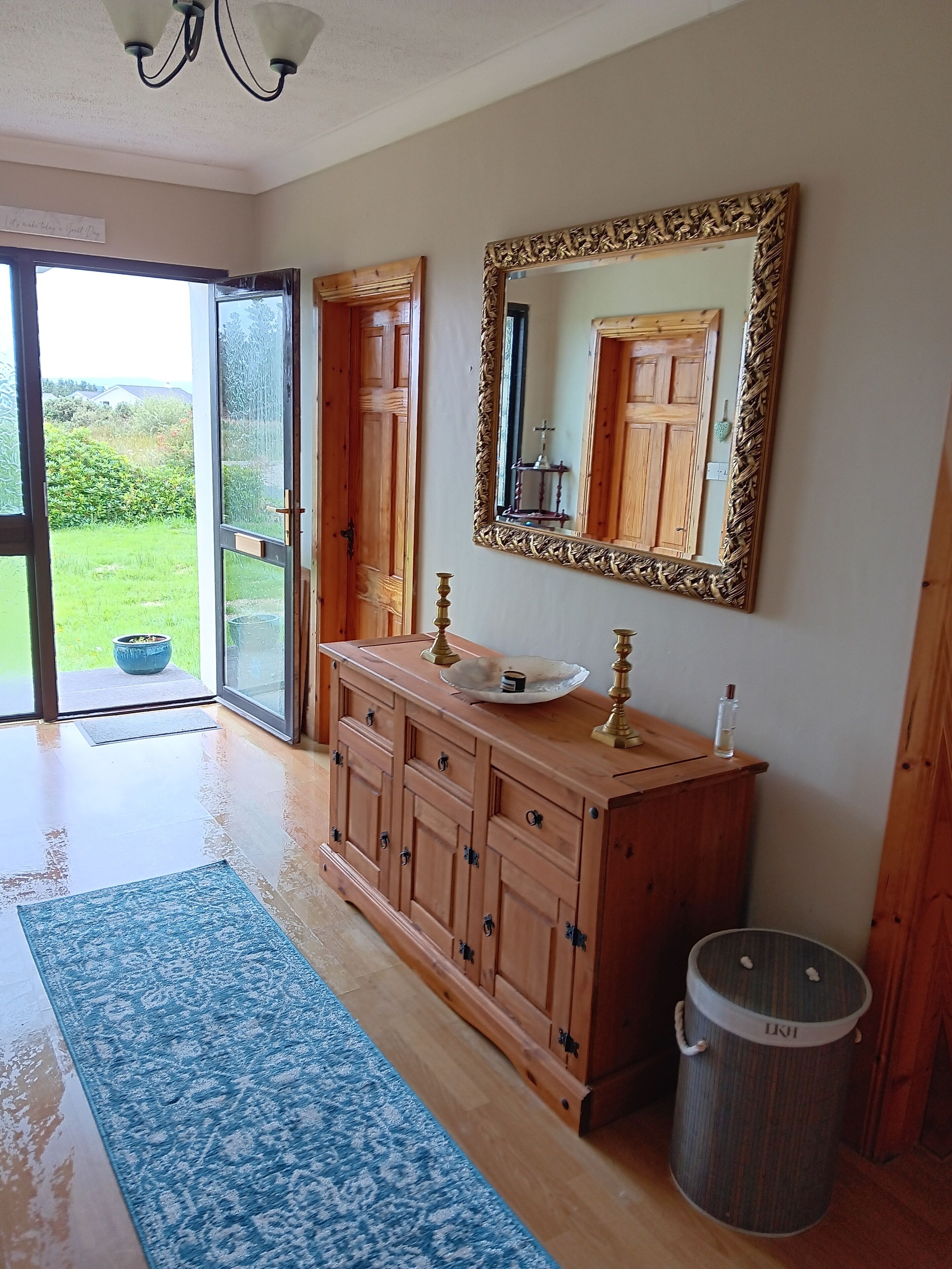 A bathroom with a wooden vanity, a large mirror, and a glass door leading to a garden.