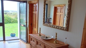 A bathroom with a wooden vanity, a large mirror, and a glass door leading to a garden.