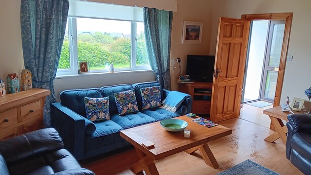 A cozy living room with a blue sofa, wooden coffee table, and a television.