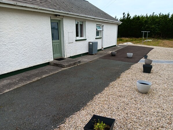 A white house with a green door, a small porch, and a gravel driveway. - Peaceful home in Ranafast at the edge of the Atlantic Ocean. (Ranafast)