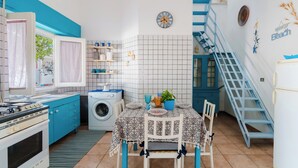 Una cocina funcional con lavadora, estufa y mesa de comedor con sillas.