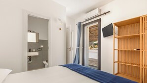 A bedroom with a bed, a wooden wardrobe, a television, and a bathroom with a mirror and sink. - Villa Petricore by Perle di Puglia (Salve)