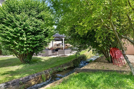 A riverside patio with outdoor seating, a small bridge, and a gazebo.. Guest Room “La Simple” for 2 with Pool in a Peaceful Setting