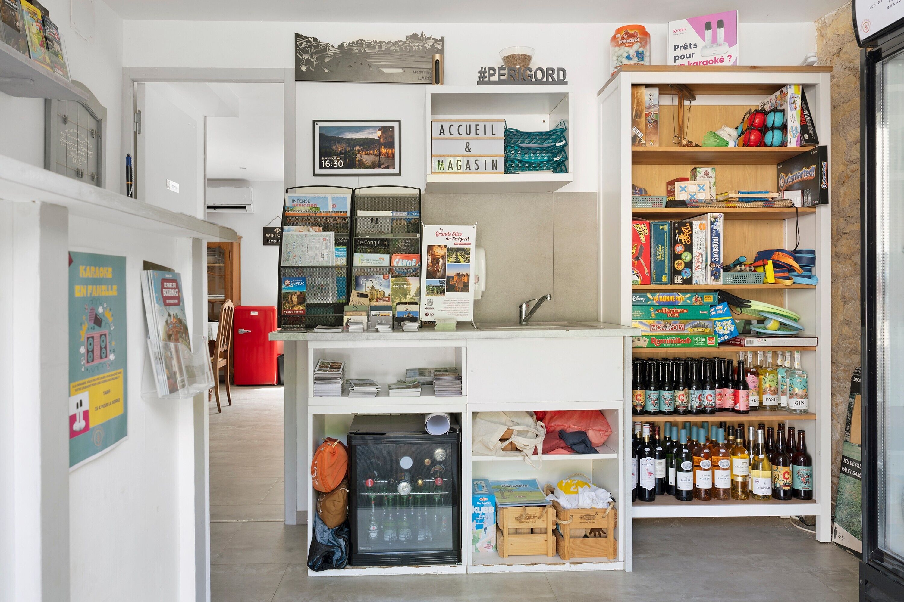 Una habitación ordenada con kitchenette, un refrigerador, estante con varios objetos y una pared con un reloj.