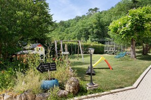 A garden area with a directional sign, a playground with a slide, and a gazebo structure.