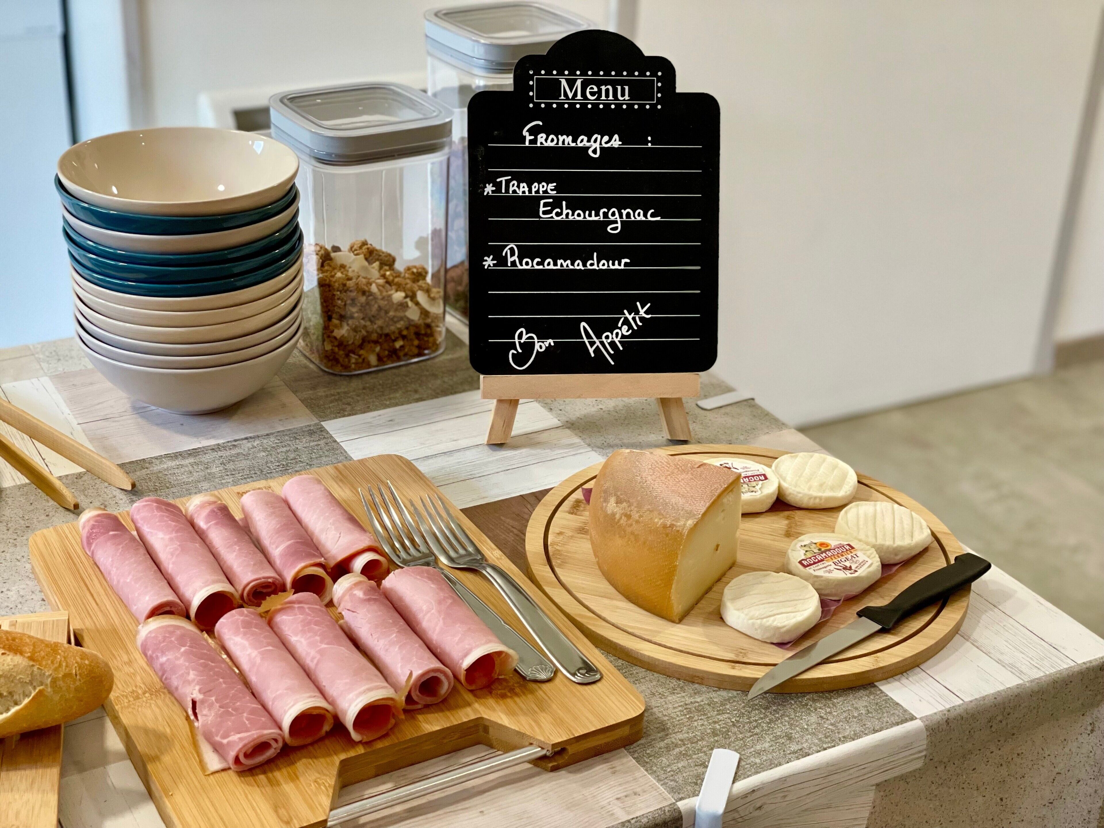 A meal setup with sliced ham, cheese, and crackers on a wooden board, with a menu sign in the background.