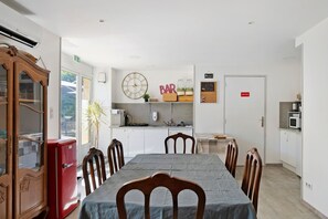 Un espace repas comprenant une table, des chaises, une horloge, une enseigne de bar et un réfrigérateur.