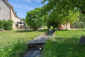 Un espace extérieur paisible agrémenté d’un petit élément décoratif aquatique, d’un sentier et d’un bâtiment doté d’une antenne parabolique.