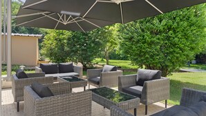 Un patio exterior con mobiliario de mimbre y una sombrilla grande.