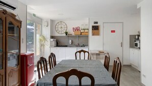 Un comedor con una mesa, sillas, un reloj, un refrigerador y una zona de cocina.