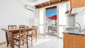 A modern kitchen with a wooden dining table and chairs, a built-in oven, and a large window with a red umbrella outside.