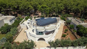Ein modernes Gebäude mit einer Solaranlage auf dem Dach, umgeben von Bäumen und einem gepflasterten Innenhof.