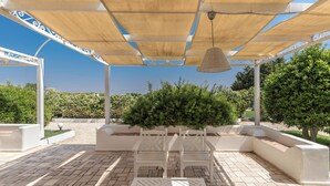 An outdoor patio with white furniture, a pergola with a woven shade, and a view of greenery. - Il Gelsomino BIanco by BarbarHouse (Mottola)
