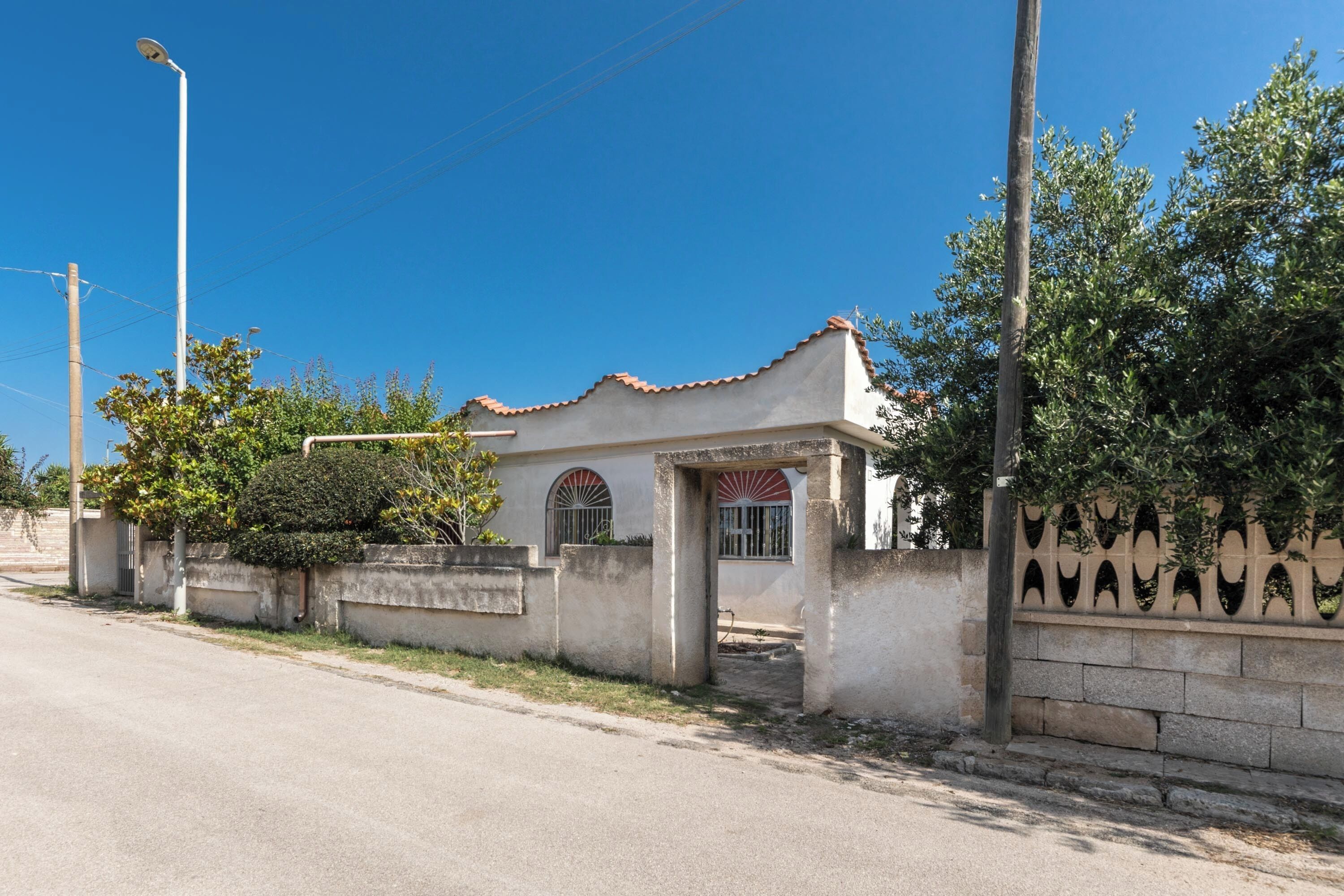 Un piccolo edificio a un piano con tetto in tegole e ingresso chiuso da un cancello.