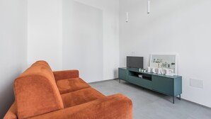 Un soggiorno moderno con un divano, un mobile TV color petrolio e un quadro appeso al muro.