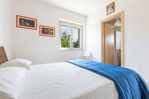A bedroom with a bed, two framed pictures, a window, and a door. - Villa Matilda by Perle di Puglia (Ostuni)