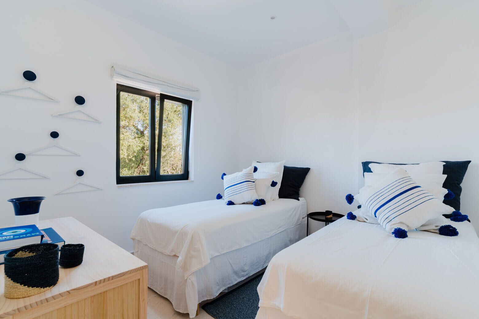 Une chambre avec deux lits, une fenêtre et un bureau avec un panier.