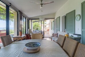 A room with a dining table, chairs, a ceiling fan, and a view of the outdoors.