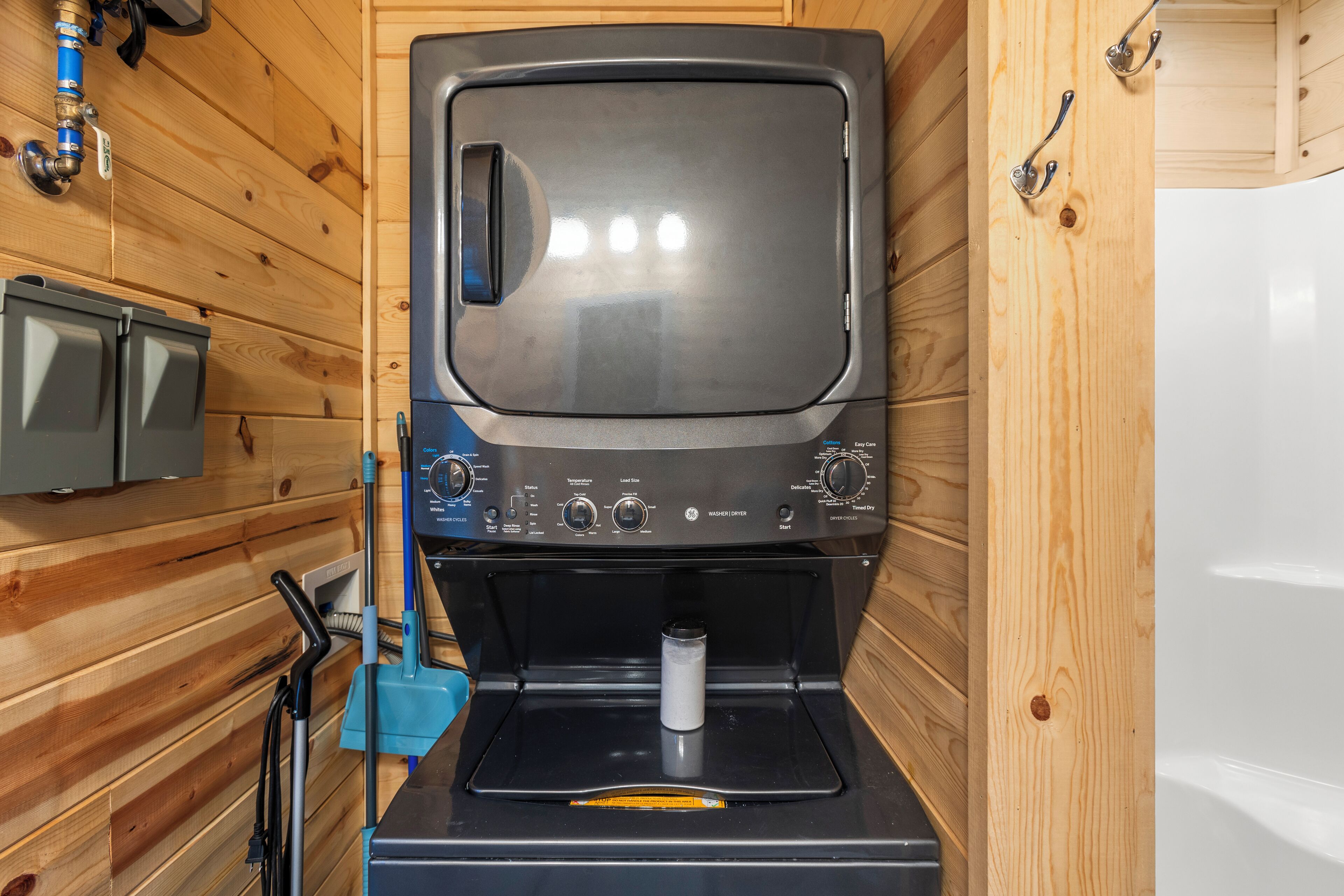A compact, wood-paneled room with a built-in washer and dryer, a small sink, and a blue towel rack.