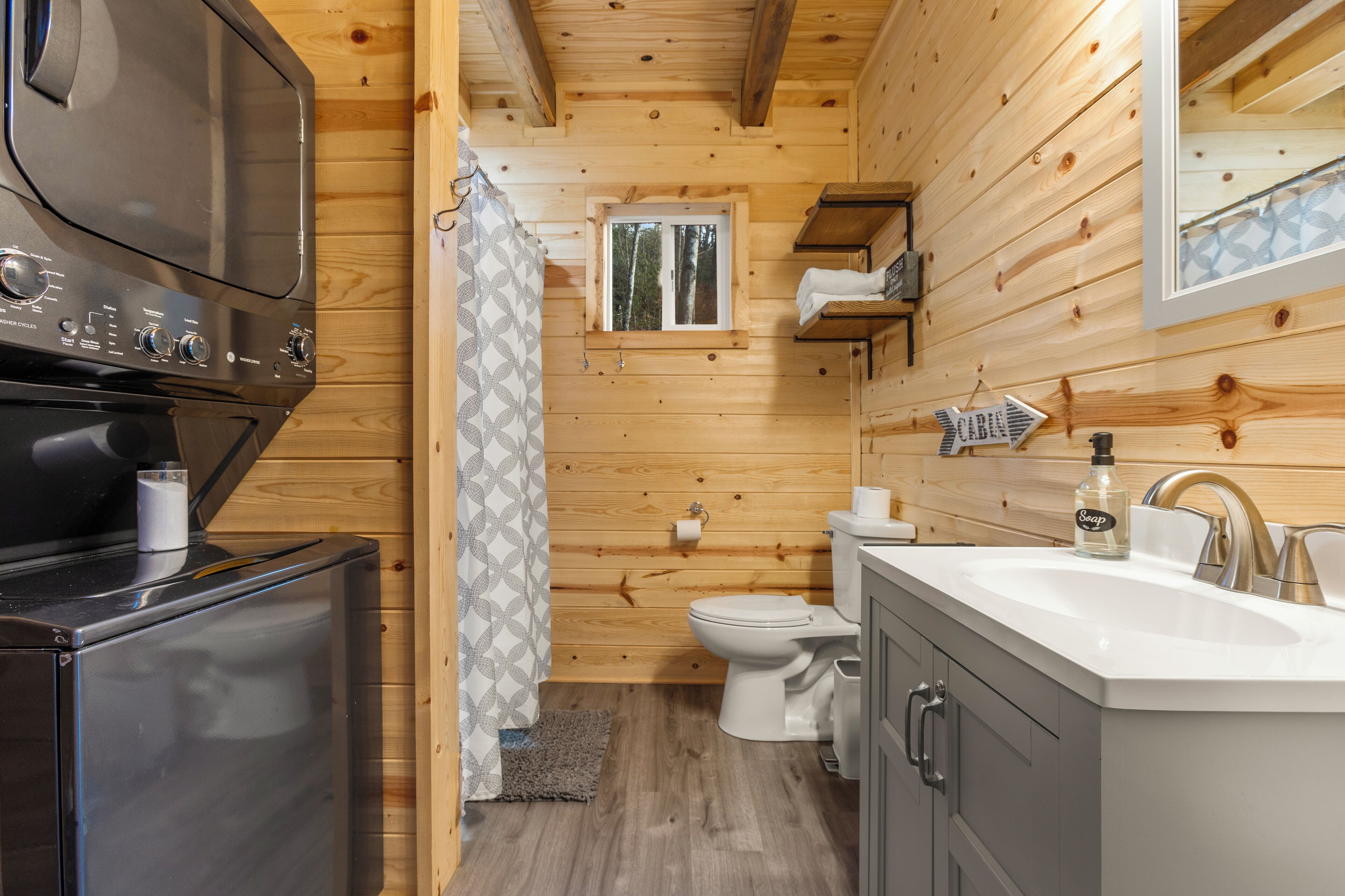 Una cabaña de madera compacta con kitchenette, inodoro y lavamanos.