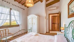 A bedroom with a bed, a wardrobe, a bench, and a window with curtains. - Agriturismo Rebarco (Castelfiorentino)