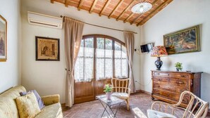 A cozy living room with a sofa, two wicker chairs, a wooden cabinet, and a TV. - Agriturismo Rebarco (Castelfiorentino)