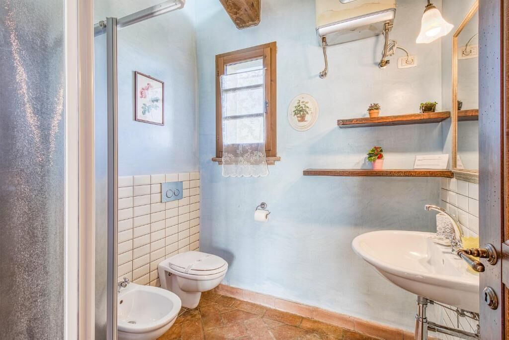 A bathroom with a toilet, bidet, sink, and shelves with plants.