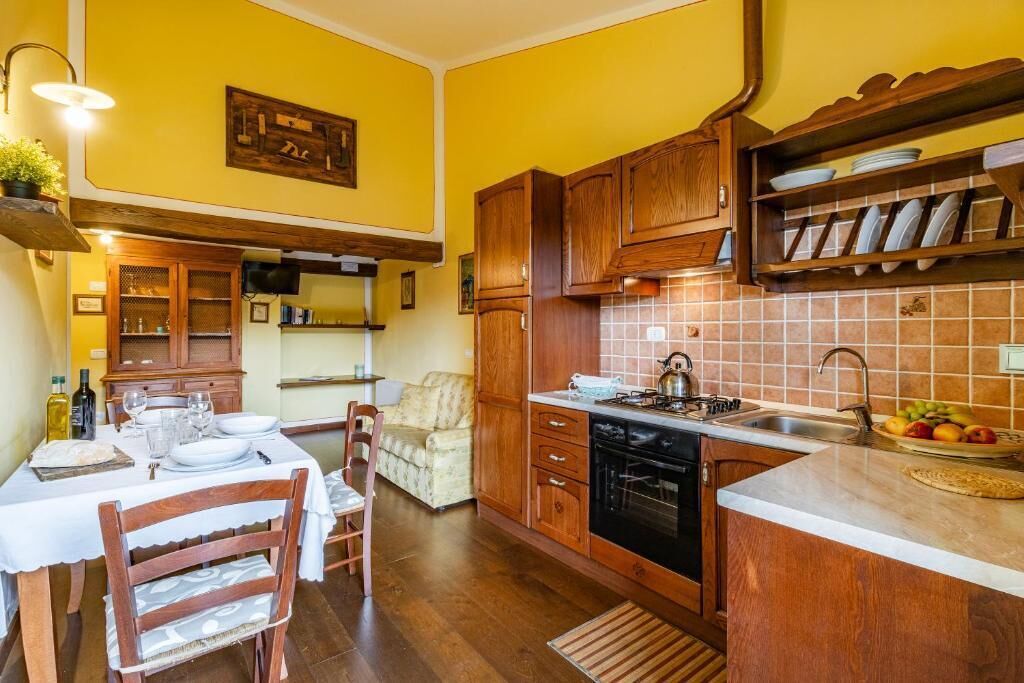 A compact kitchen with wooden cabinets, a tiled backsplash, and a dining area with a table set for two.