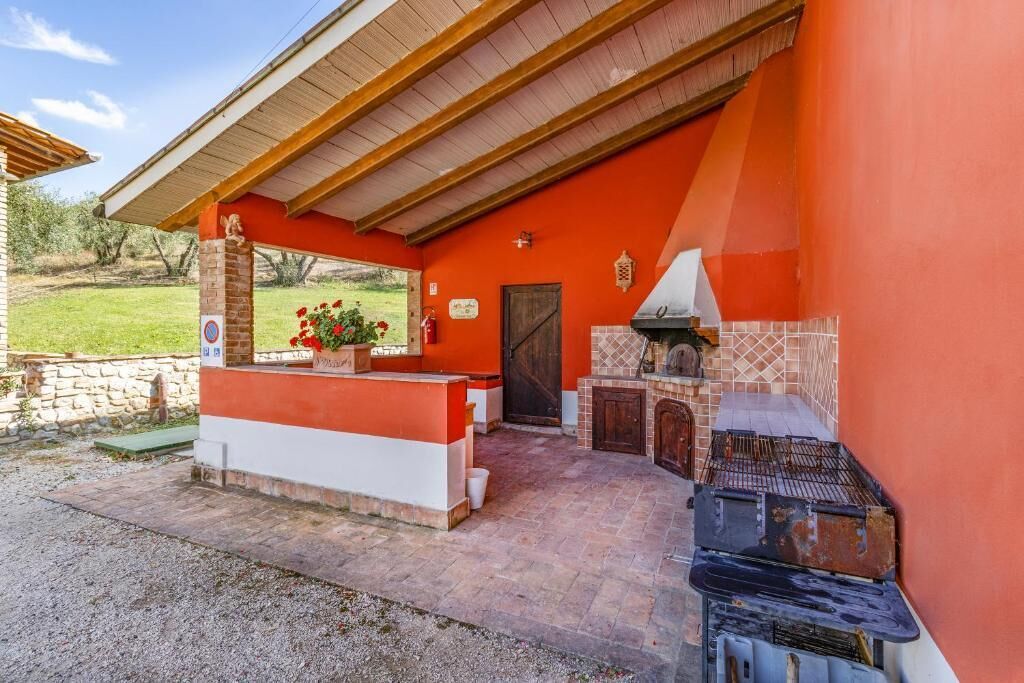 An outdoor patio with a barbecue area, a stone wall, and a wooden pergola.