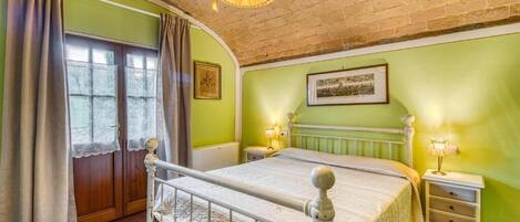 A bedroom with a bed, two bedside tables, a window with curtains, and a picture on the wall.