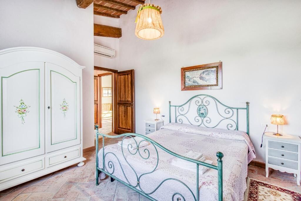 A bedroom with a bed, nightstands, a wardrobe, and a hanging light fixture.
