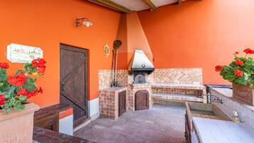 An outdoor kitchen area with a tiled backsplash, a grill, and potted plants.