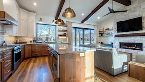 Une cuisine moderne avec des meubles en bois, un îlot central et une cheminée intégrée.