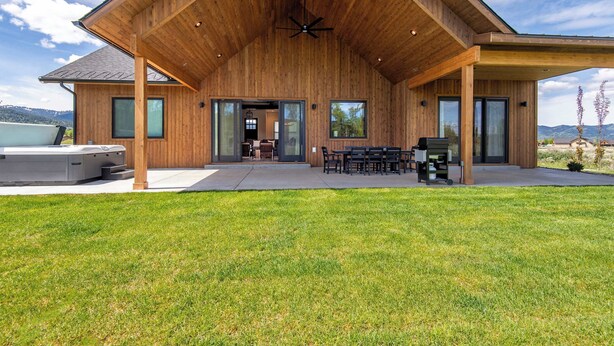 Une maison moderne en bois dotée d’un patio couvert, d’un espace salon extérieur et d’un jacuzzi.