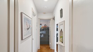 A narrow hallway with wooden flooring, white walls, and doors leading to other rooms. - Tulsa Stay Near Midtown & Tulsa Expo Center (Tulsa)