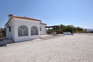 A white building with a tiled roof, arched windows, and a gravel driveway. - Cozy casita in the countryside with swimming pool, near Málaga (Almogía)