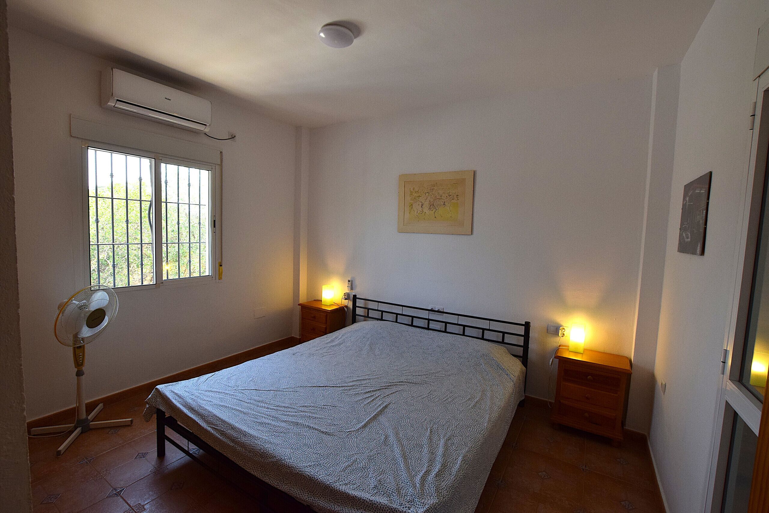 Une chambre à coucher avec un lit, une fenêtre, un climatiseur et des lampes de chevet.