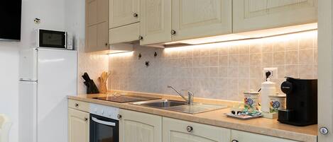 A kitchen with a microwave, oven, sink, and coffee maker.
